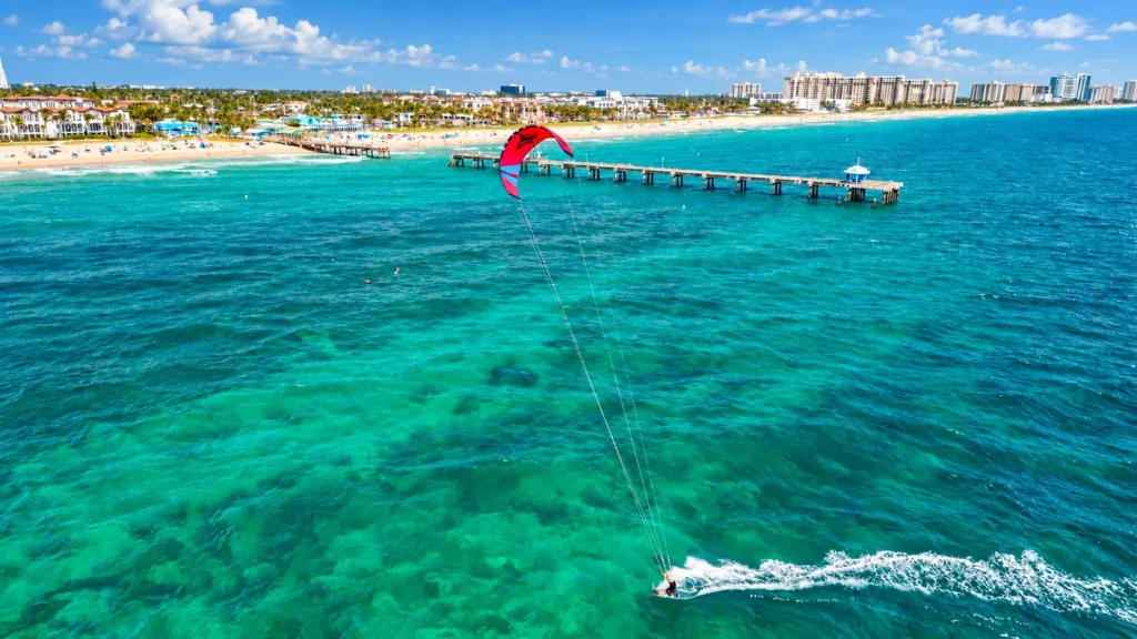Boat and kite activity near a beach pier